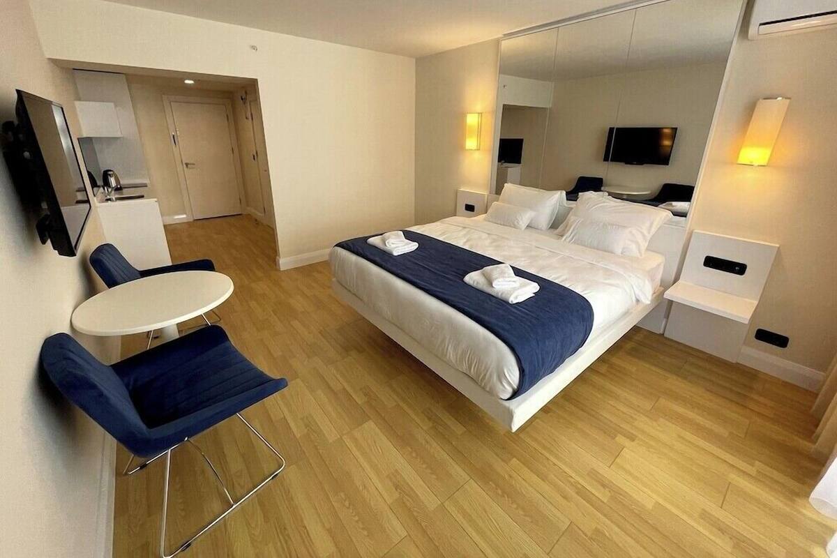 Ein Hotelzimmer mit einem Bett, einem Schreibtisch, einem Stuhl, einem Fernseher und einem Spiegel.