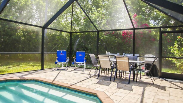 A covered outdoor area with a pool, chairs, and a table. - Family Friendly, Great Pool and Easy Bowman's Beach Access (Sanibel)