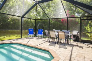 A covered outdoor area with a pool, chairs, and a table. - Family Friendly, Great Pool and Easy Bowman's Beach Access (Sanibel)