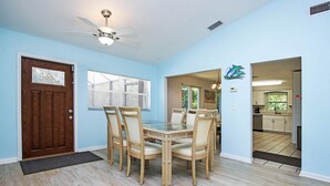 A dining area with a wooden table and chairs, a ceiling fan, and a view into the kitchen. - Family Friendly, Great Pool and Easy Bowman's Beach Access (Sanibel)