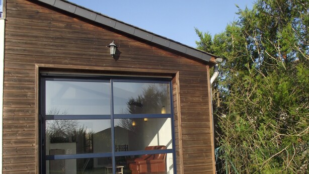 A modern building with a large glass door and wooden exterior. - Countryside at the foot of Mont Saint Michel (Roz-sur-Couesnon)