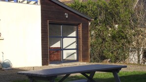 A picnic table in a garden area with a wooden building in the background. - Countryside at the foot of Mont Saint Michel (Roz-sur-Couesnon)
