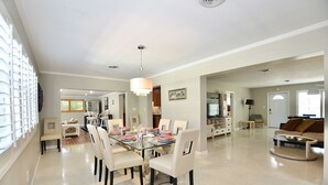 A spacious living room with a large glass dining table, comfortable seating, and a cozy fireplace area.