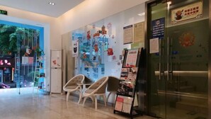 Un vestíbulo de hotel con mostrador de recepción, zona de estar y una pared de vidrio con obras de arte.