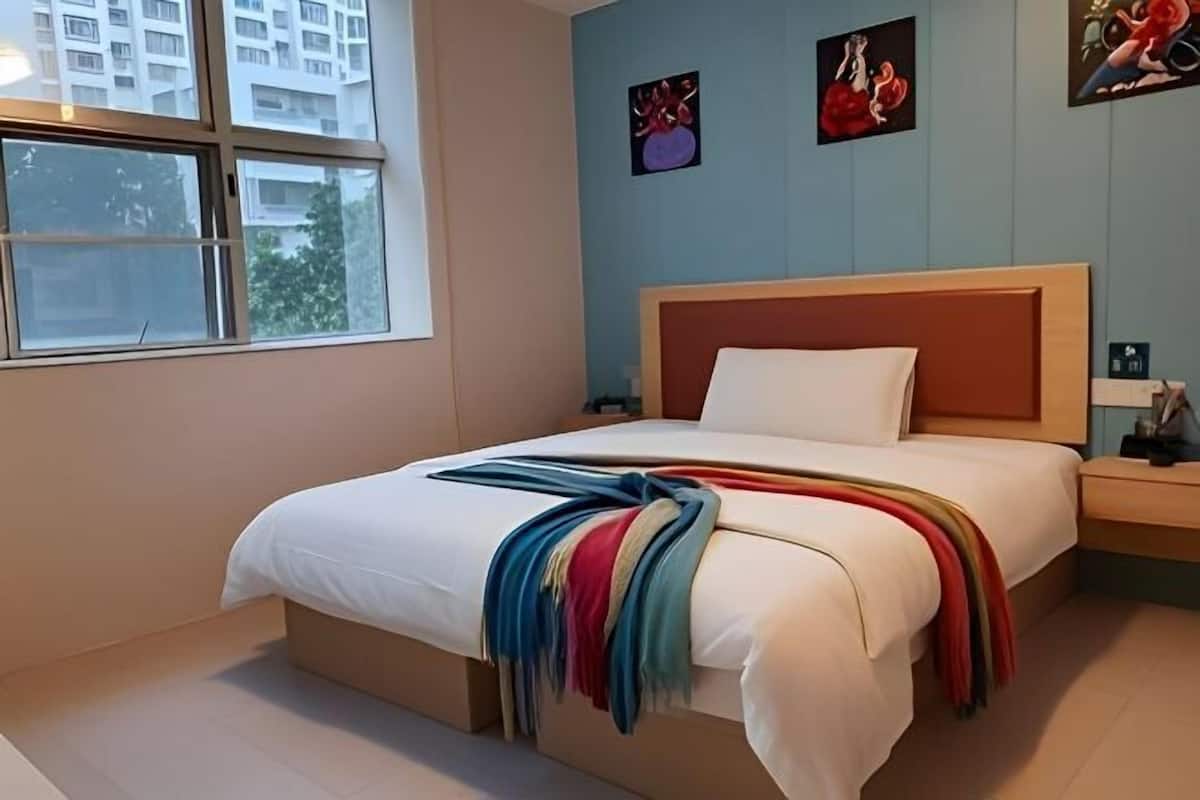 Quarto com cama, mesa de cabeceira, janela e decoração na parede.
