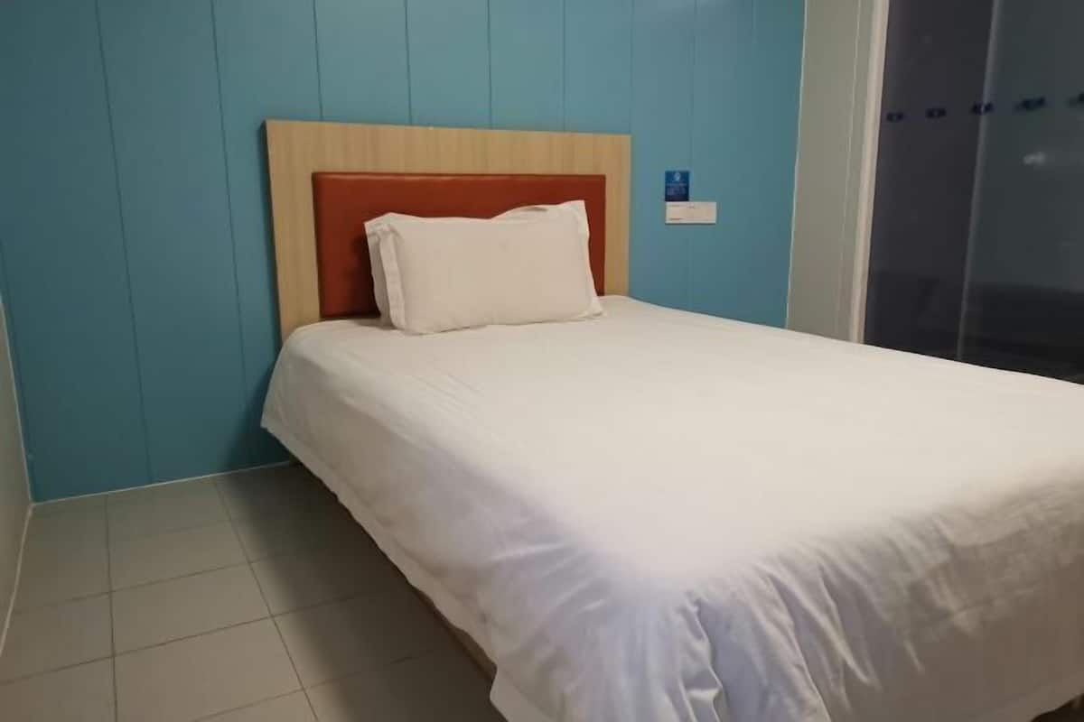 Quarto de hotel com cama, cabeceira de madeira e parede azul.