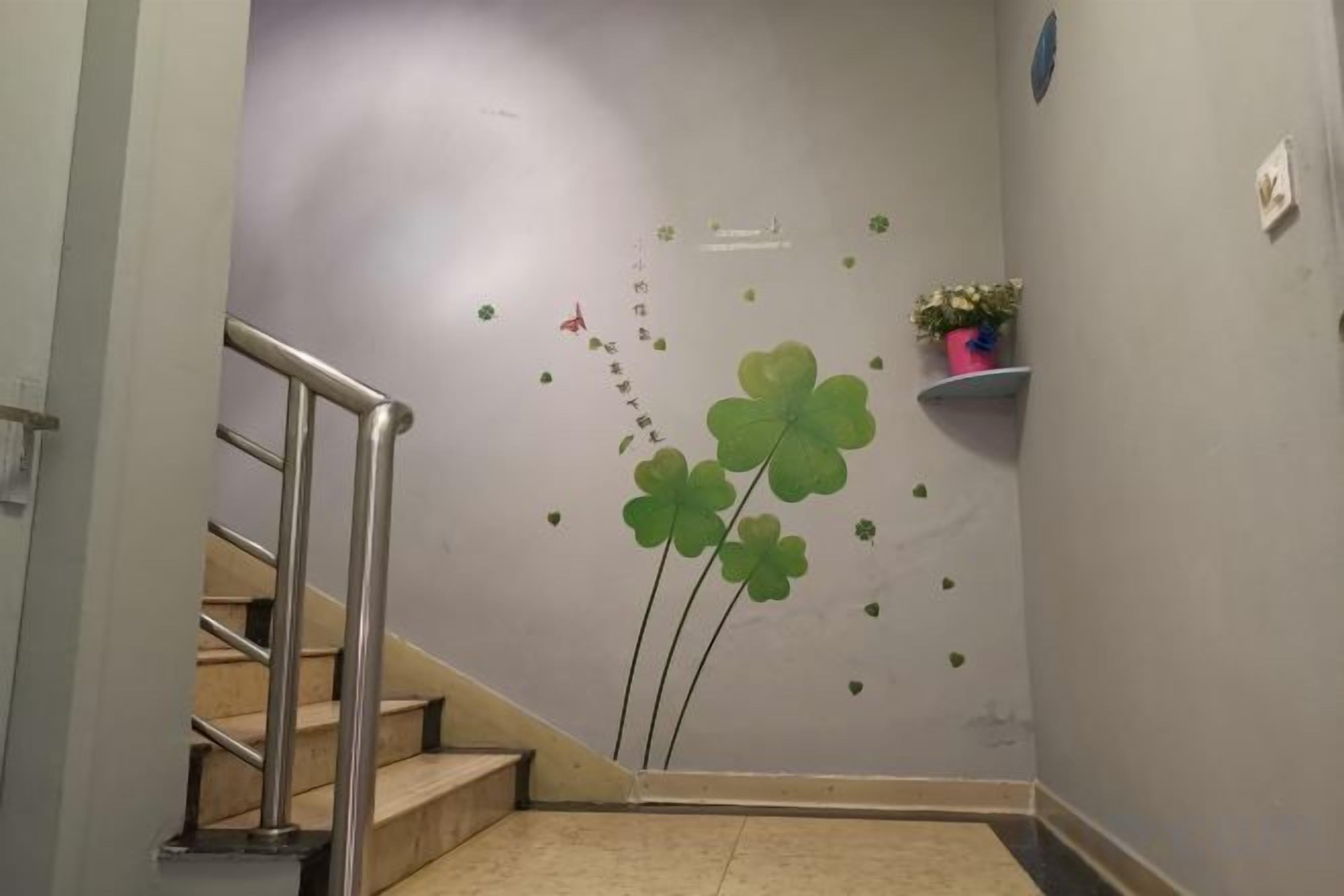 A staircase with a handrail, a wall with clover decorations, and a small shelf with a plant.
