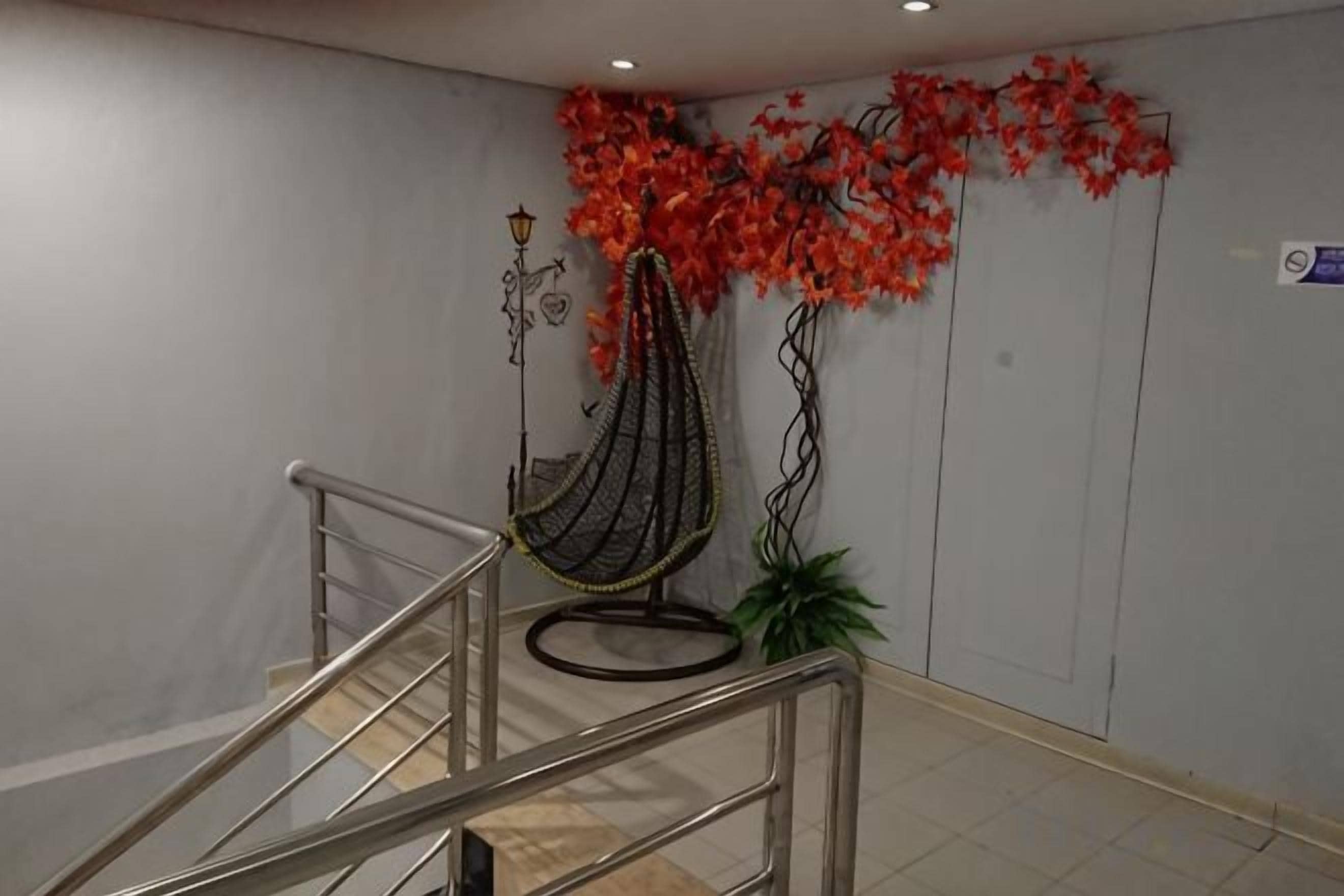 Una escalera con barandilla de metal, un sillón colgante y una pared decorada con motivos florales rojos.