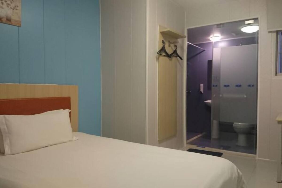 Quarto de hotel com cama, box de chuveiro e banheiro pequeno.