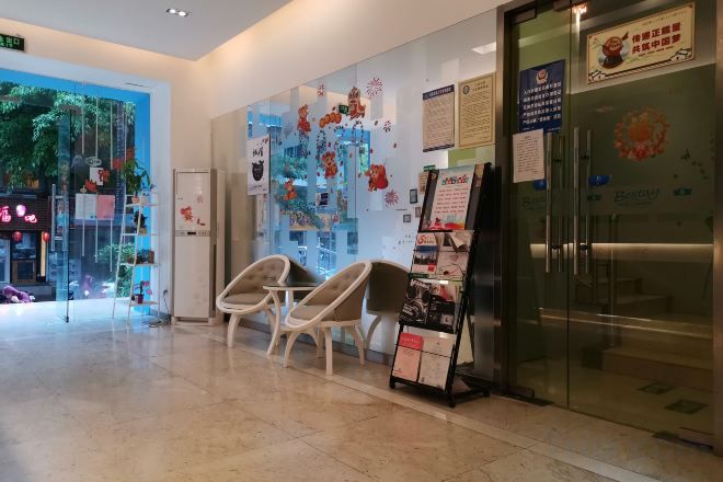 A reception area with a glass door, a seating area with chairs, and a wall with various posters and notices.