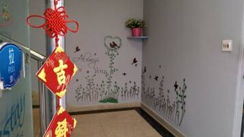 A hallway with a blue sign, a red and gold decoration, and a wall with floral and butterfly decals.