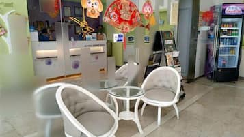Zona de recepción con mostrador, sillas y máquina expendedora.