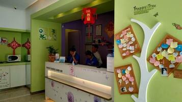 Un mostrador de recepción con un letrero que dice 'Happy Tree' y un tablón de anuncios con notas e imágenes.