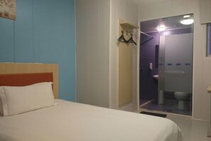 A hotel room with a bed, a shower area, and a bathroom. - Baishijie Hotel (Shantou)