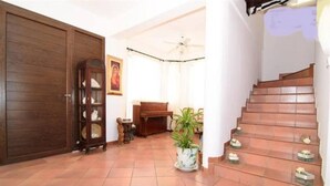 A spacious hallway with a wooden door, a wooden cabinet, a piano, a potted plant, and a staircase. - 4 Bedroom Villa With Private Pool Near Beach (Oroklini)