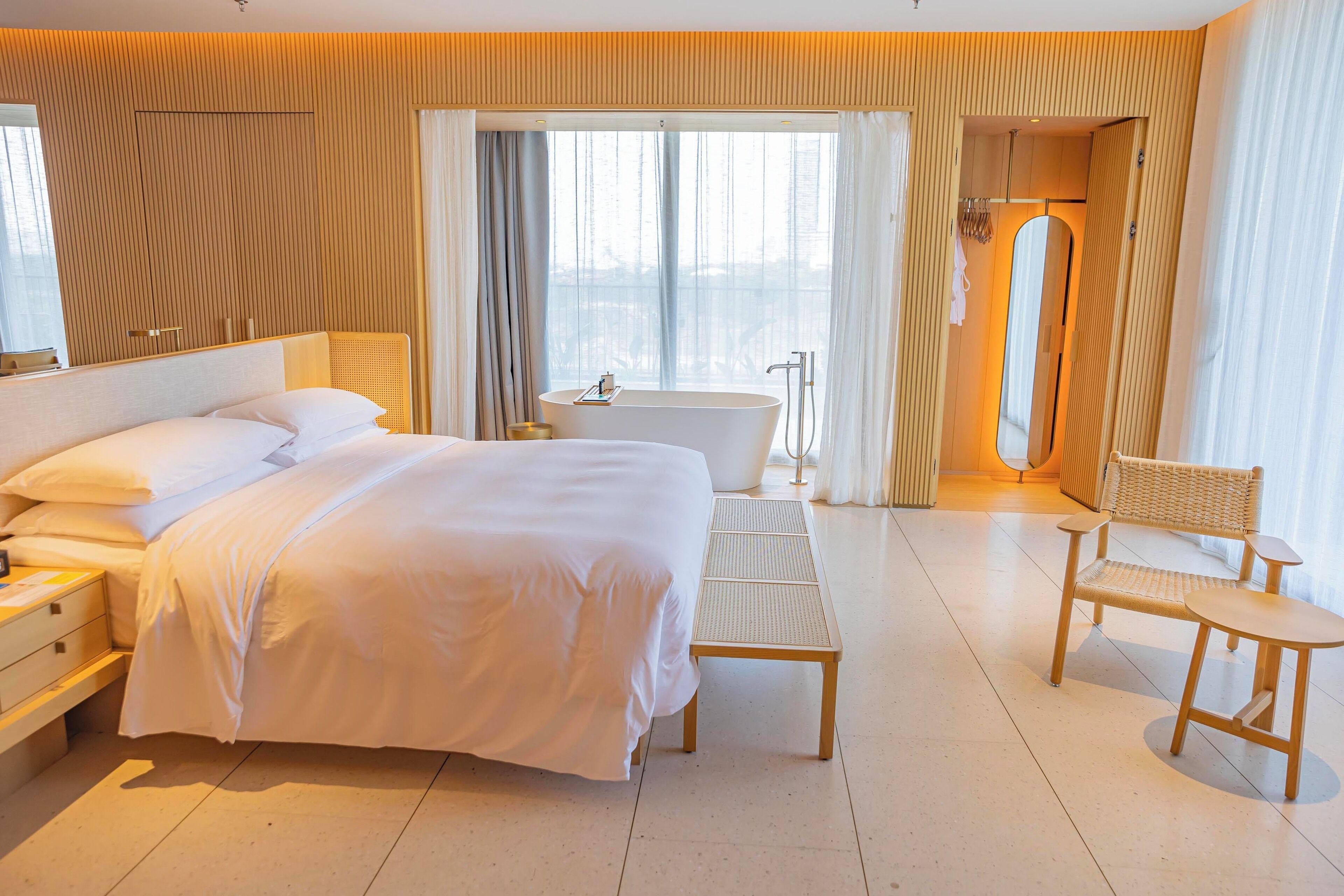 Una habitación de hotel con una cama grande, una bañera, una silla y una mesita.