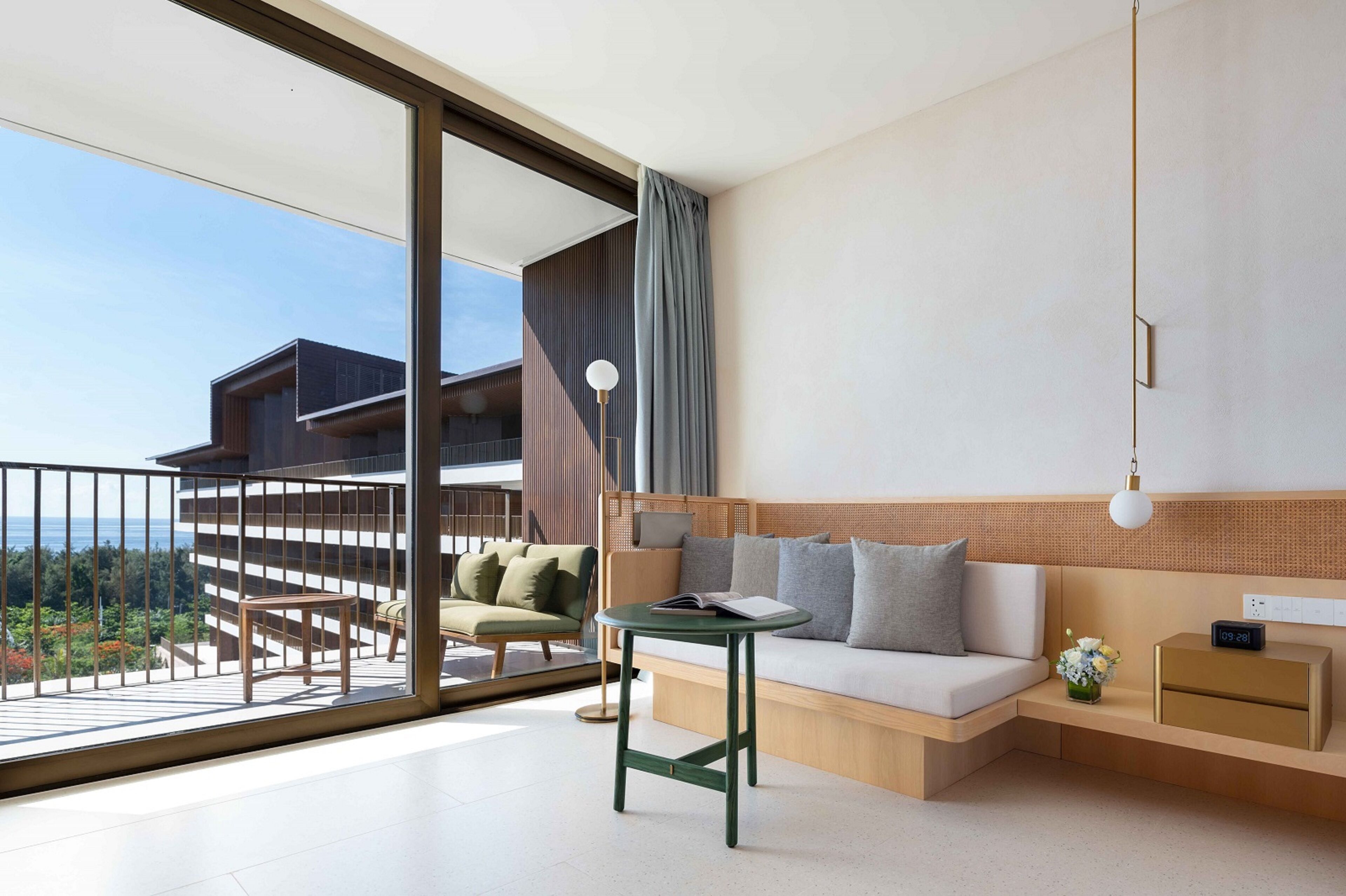 A modern living room with a sofa, a small table, and a view of a building through a glass door.