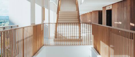 A multi-level interior with a central staircase, wooden railings, and a view of the city.