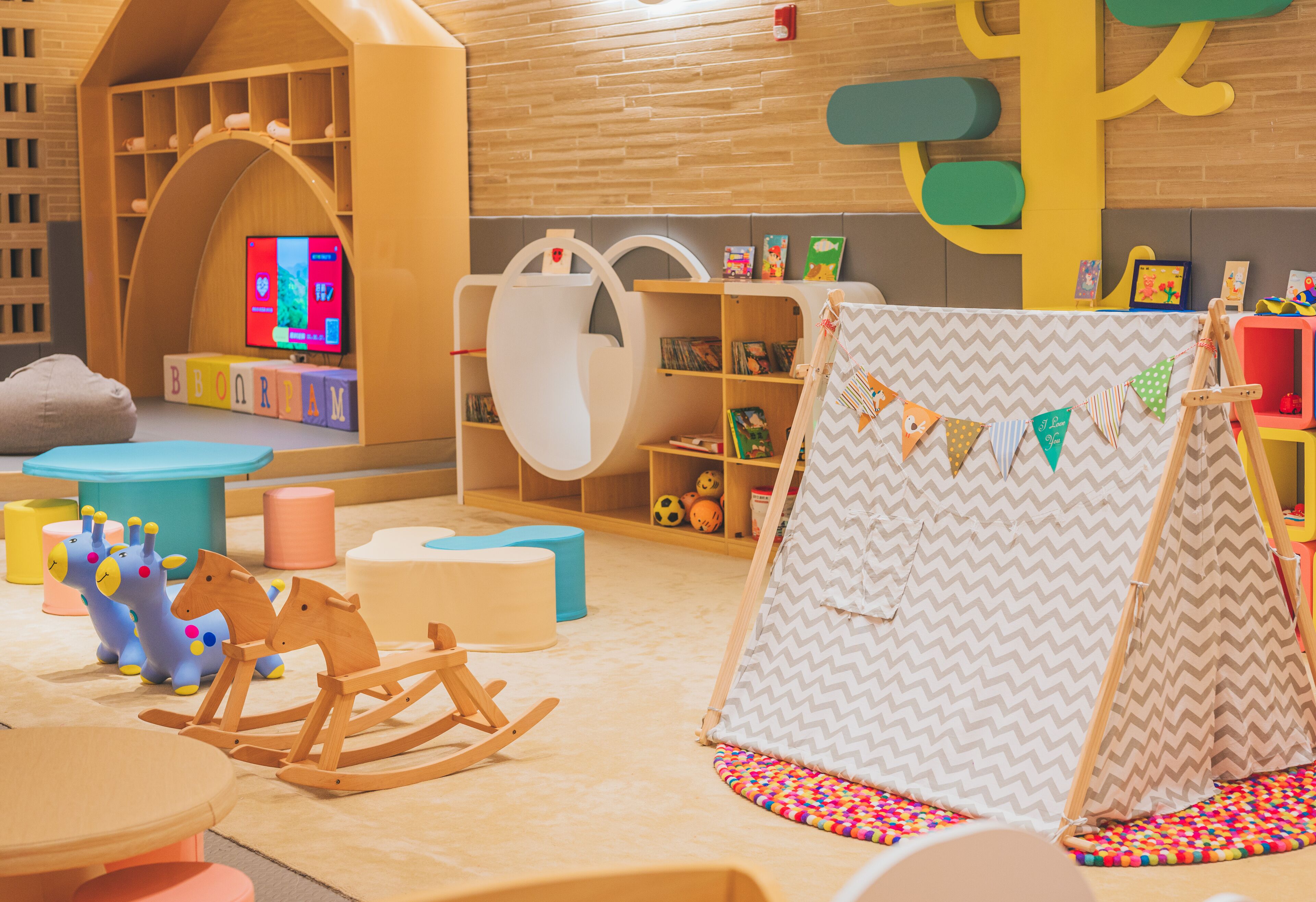 A children's playroom with a playhouse, rocking horses, and a teepee.