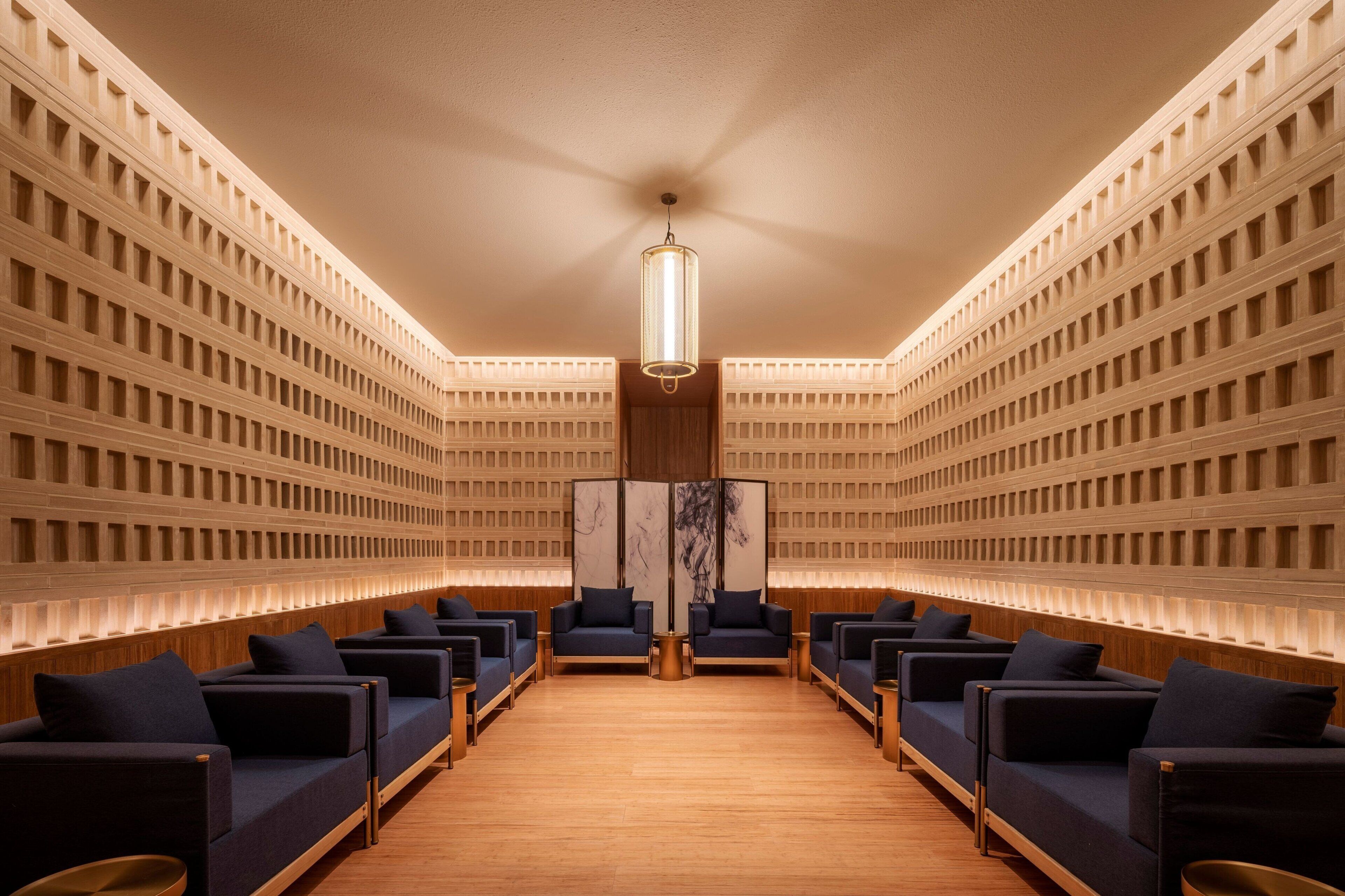 A modern hotel lobby with rows of seating and a central light fixture.