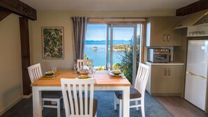 Een eetruimte met een tafel voor vier personen, een keuken met moderne apparaten en een schitterend uitzicht op zee.