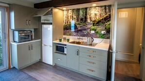 Een moderne keuken met inbouwapparatuur, een groot raam en een wanddecoratie met een bosmotief.