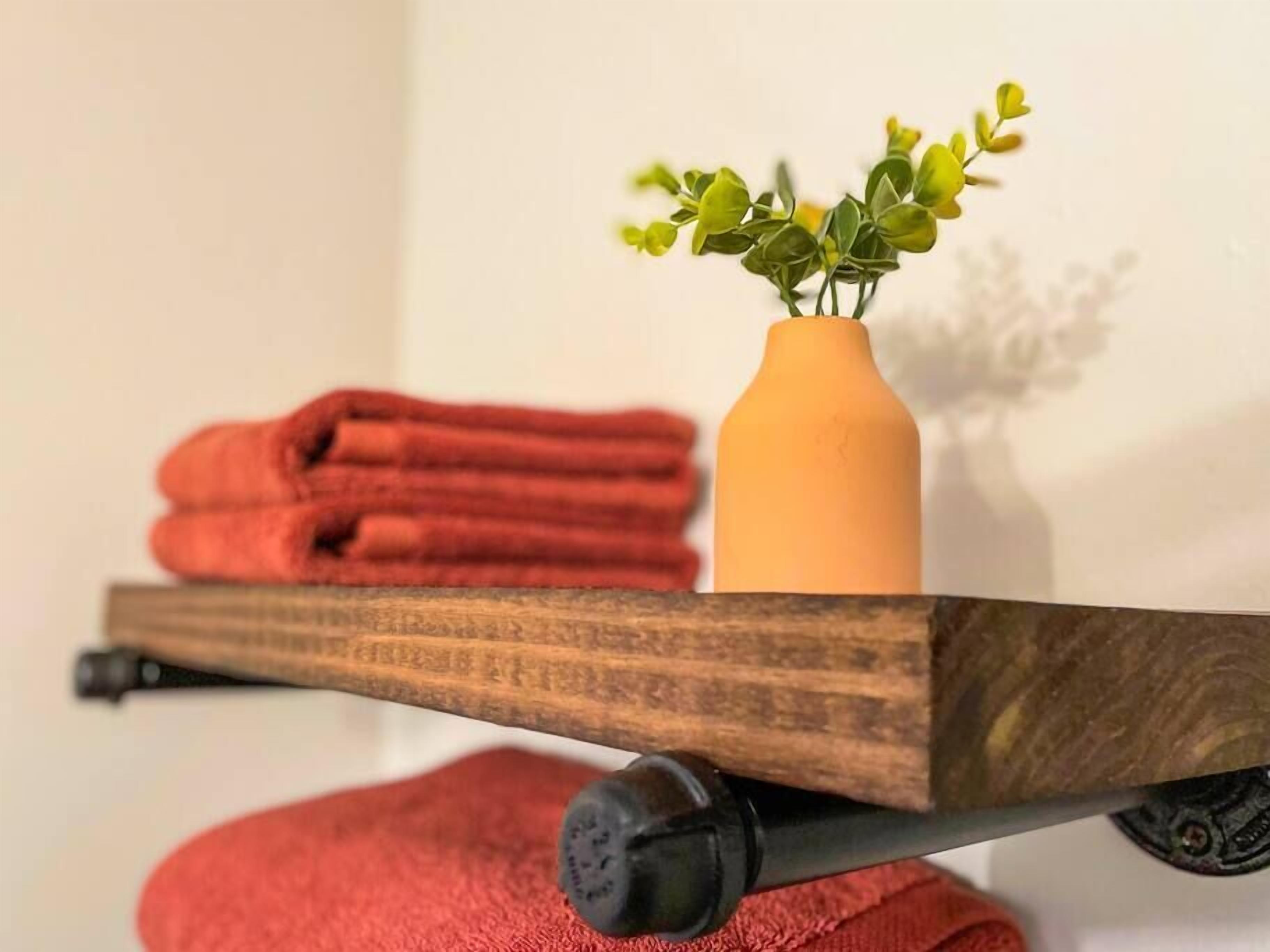 A wooden cart with a vase of green plants and folded red towels.