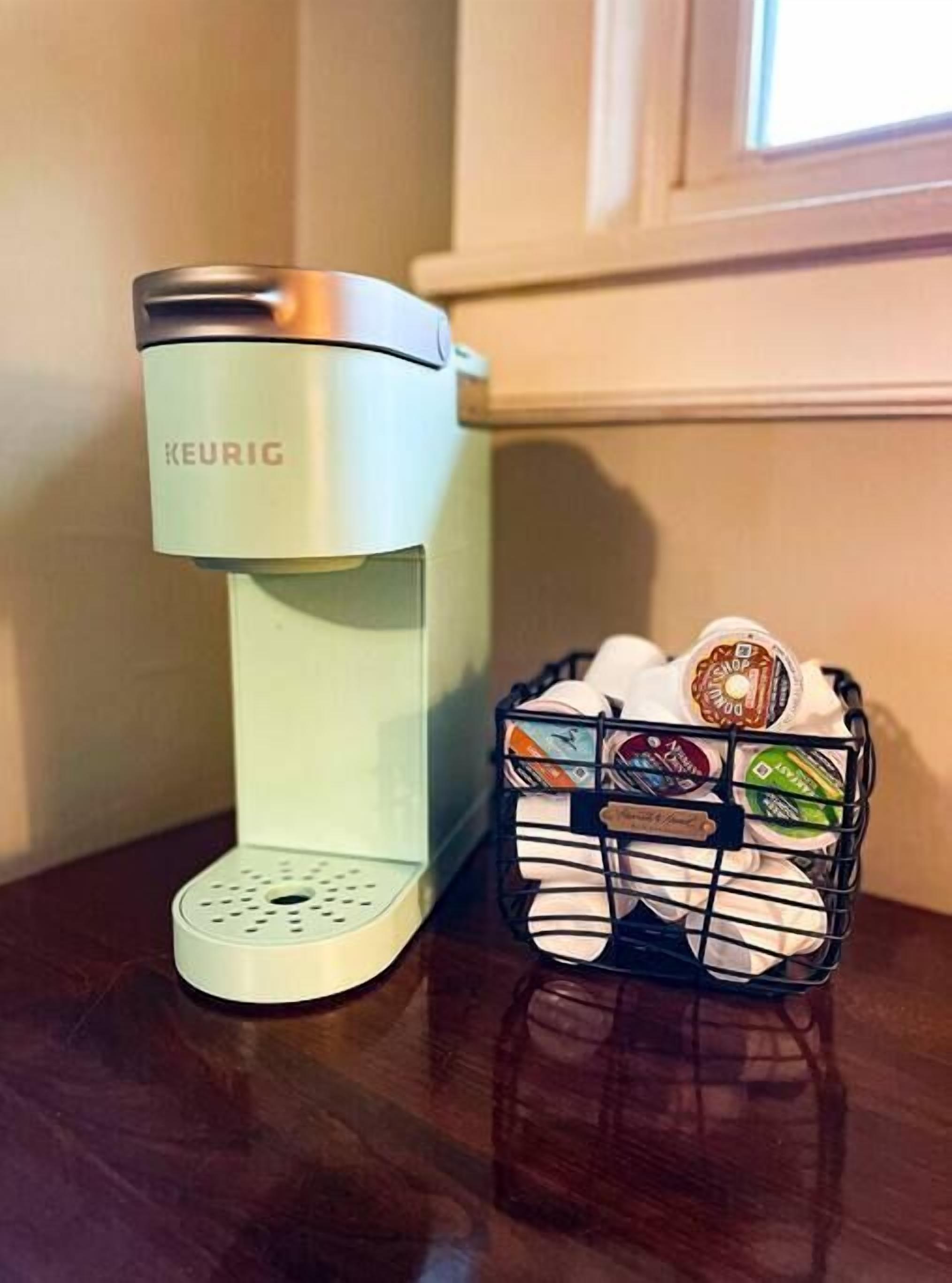 A KEURIG coffee maker and a basket of coffee pods on a wooden table.
