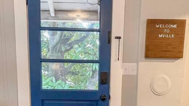 A blue door with a window, a welcome sign, and a patterned rug.