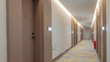 A hotel corridor with doors, a carpeted floor, and emergency exit signs.