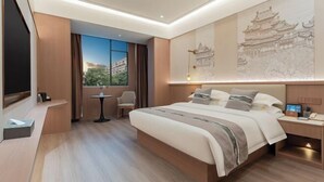 Ein Hotelzimmer mit einem großen Bett, einem Schreibtisch, einem Sessel, einem kleinen Tisch und einem Fenster mit Blick.