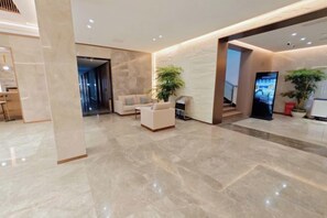 Eine moderne Lobby mit Marmorboden, einer Rezeption, einer Sitzecke und einer Treppe.