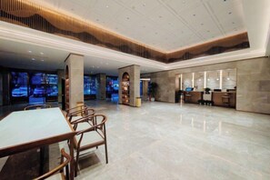 A spacious lobby with a reception desk, seating area, and a large table. - Yichang Xiazhou Yiling Hotel (Jiefang Road Pedestrian Street, Yanjiang Avenue) (Yichang)