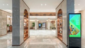 Eine geräumige Lobby mit Marmorböden, einem Empfangstresen und einer digitalen Informationsstation.