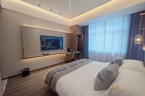 Ein modernes Hotelzimmer mit einem großen Bett, einem Schreibtisch, einem Stuhl, einem an der Wand montierten Fernseher und einem Fenster mit Vorhängen.