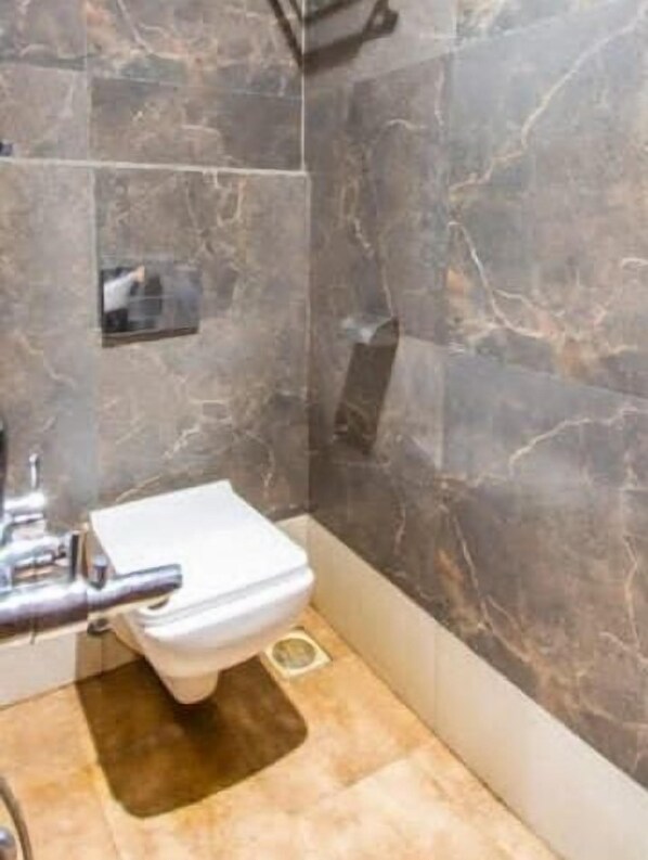 A bathroom with a toilet, a shower, and a sink.