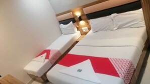 A compact hotel room with two single beds, each with a pillow and a blanket. - HOTEL RUBY (Mumbai)