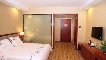 Habitación de hotel con cama, mesita de noche, televisión y puerta que da a otra habitación.