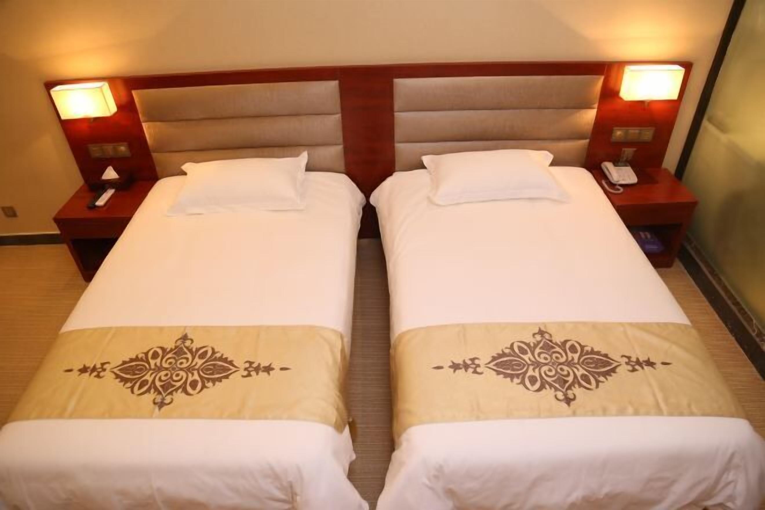A double room with two beds, bedside lamps, and a telephone on the nightstand.