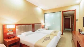 Habitación de hotel con dos camas, cabecera de madera, mesita de noche, escritorio y espejo.
