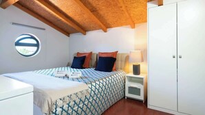 A bedroom with a bed, a nightstand, a wardrobe, and a window. - Central Duplex Porto House by HostWise (Porto)
