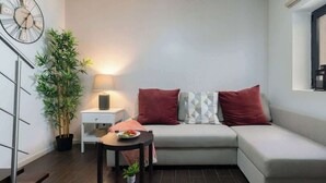 A modern living room with a sofa, a side table, a lamp, and a potted plant. - Central Duplex Porto House by HostWise (Porto)