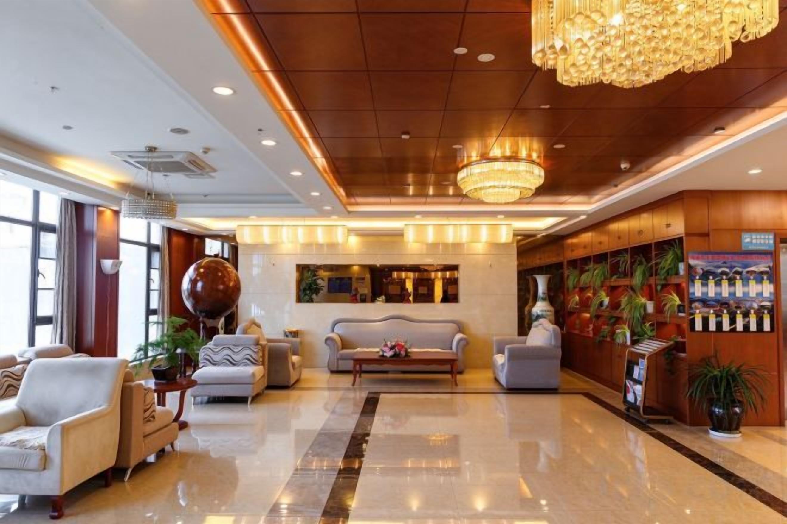 Um hall amplo com um candelabro, sofás e um balcão de recepção.
