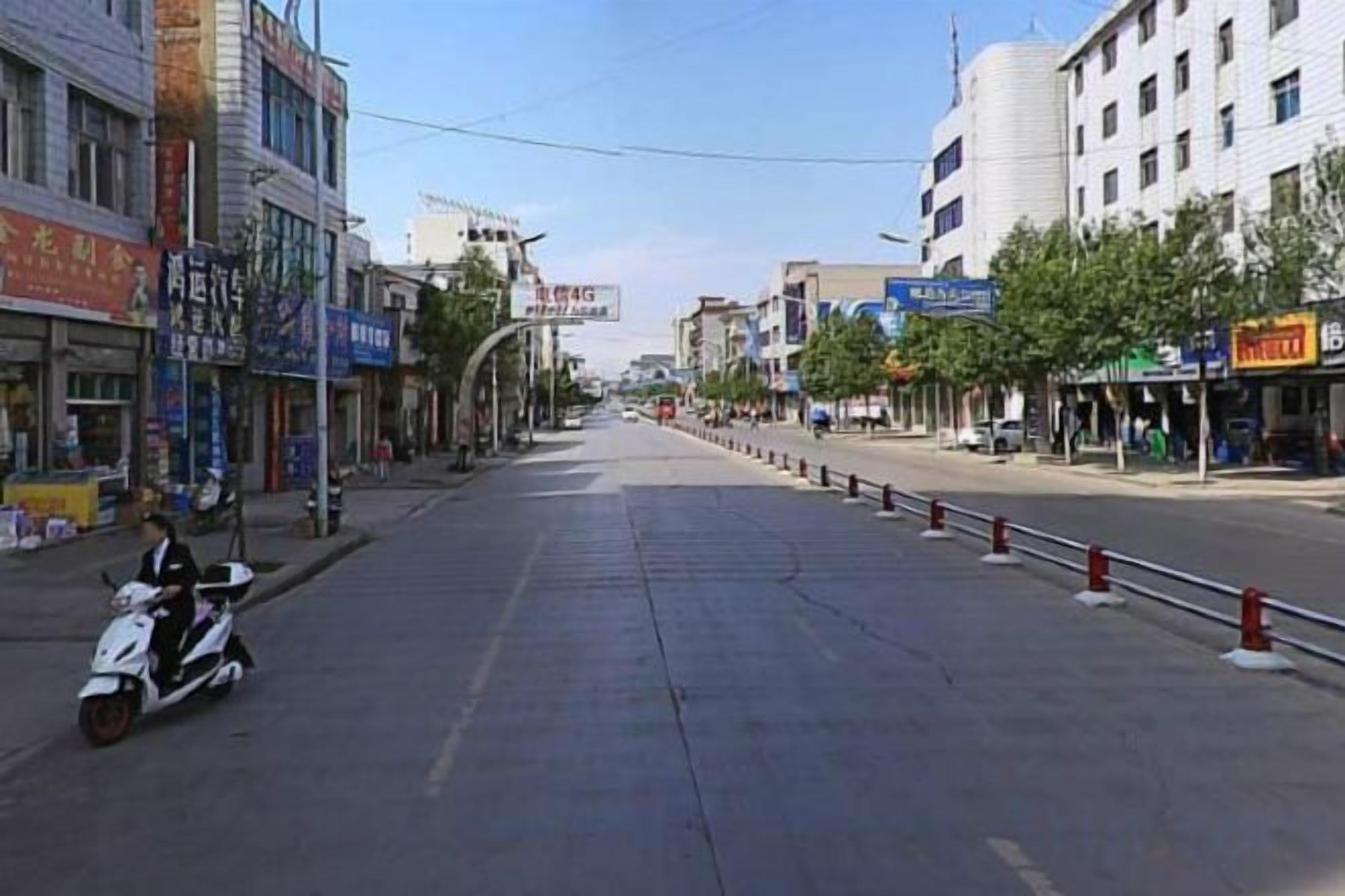 A street with buildings, a scooter, and a clear sky.
