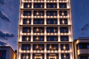 Un edificio de varios pisos con ventanas iluminadas y un diseño arquitectónico moderno.
