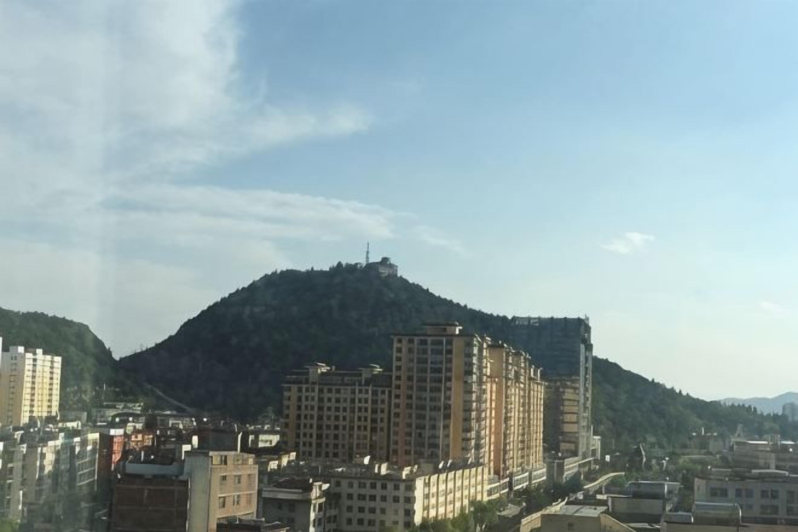 A cityscape with buildings and a hill in the background.