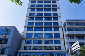 A multi-story building with a modern architectural design, featuring a prominent entrance with signage. - Qingtian Boutique Hotel (Wuyue Plaza Wanghai Park) (Zhaotong)