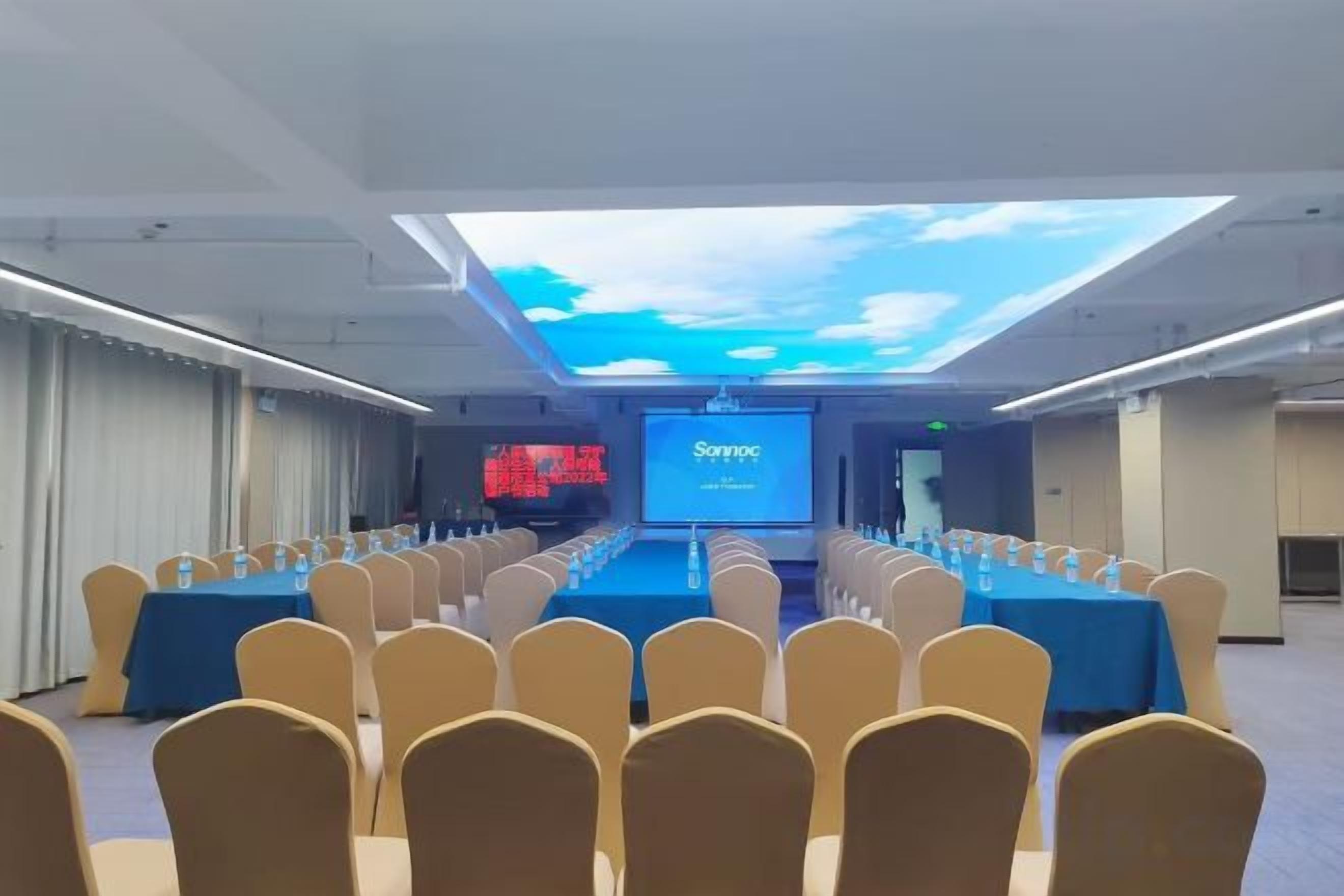 A conference room with a long table, chairs, and a presentation screen.