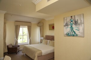 Quarto com uma cama grande, uma cadeira, uma janela com cortinas e um quadro na parede.