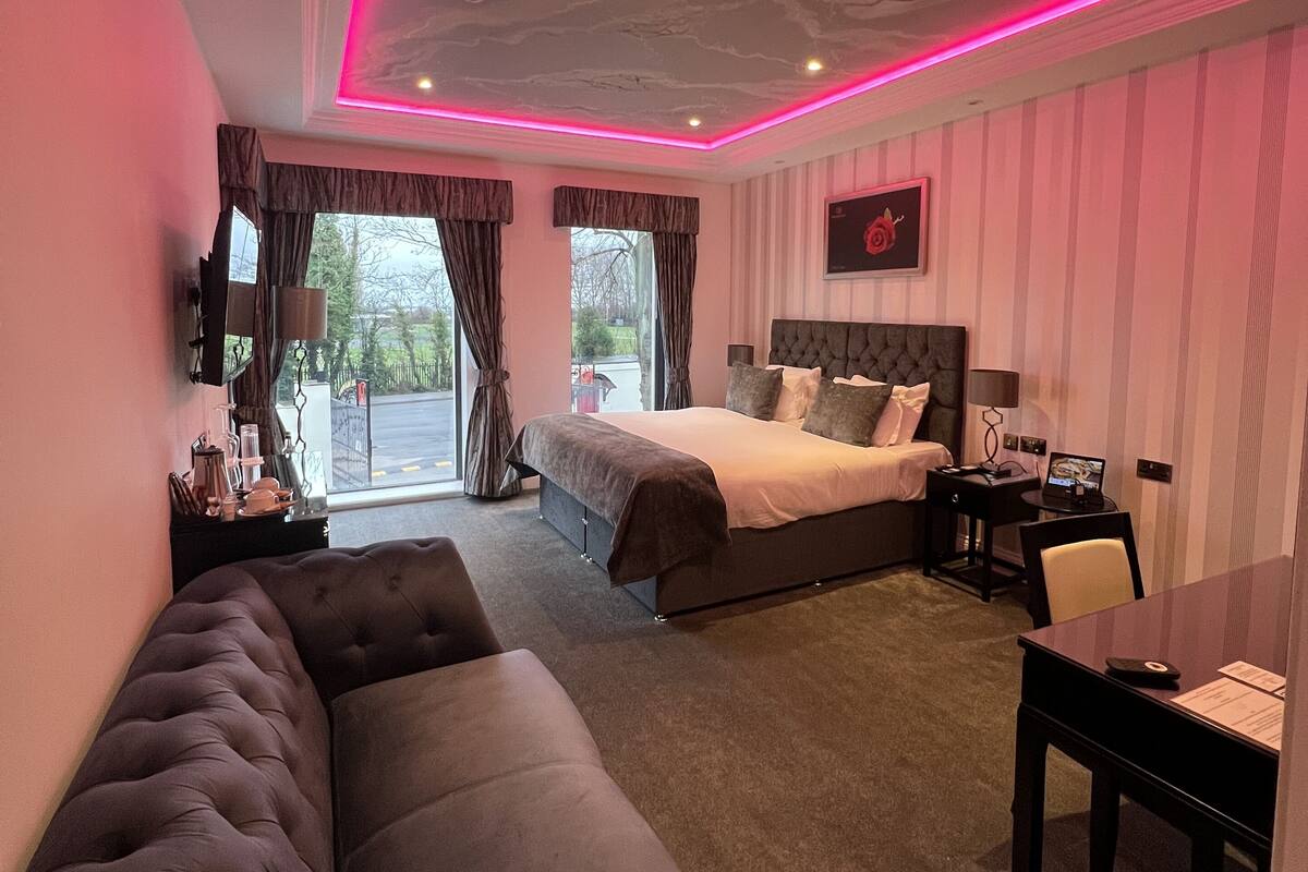 A modern bedroom with a large bed, a sofa, and a desk.